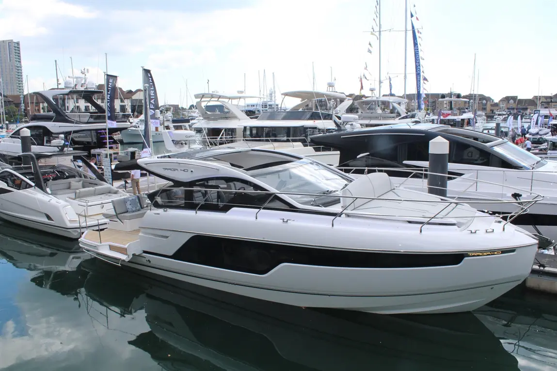 A sleek white motorboat, TARGA 40, docked among several luxury yachts at a marina on a clear day.